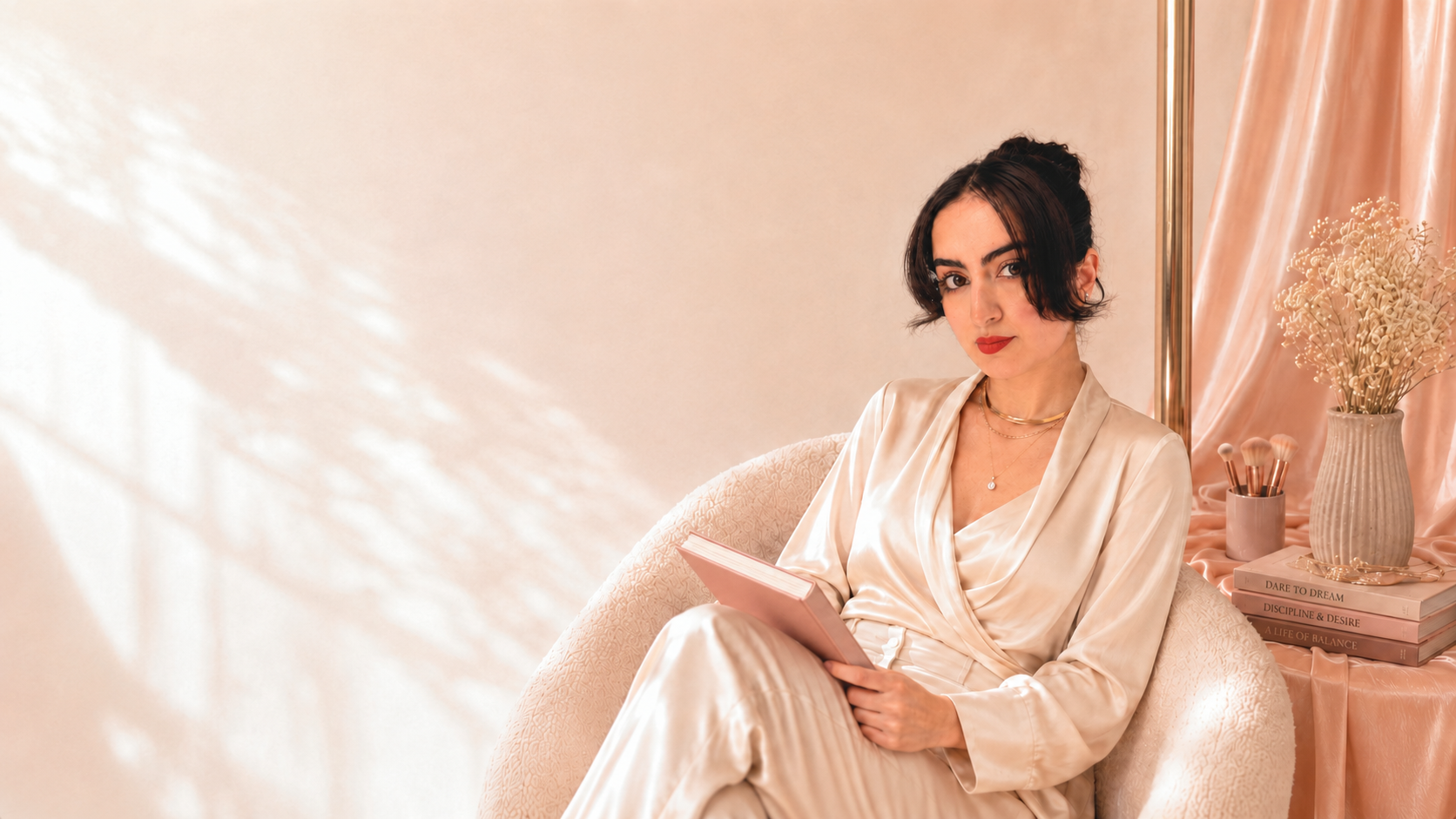 Dr. Ashley Montazer seated beside a pole, reading and applying makeup